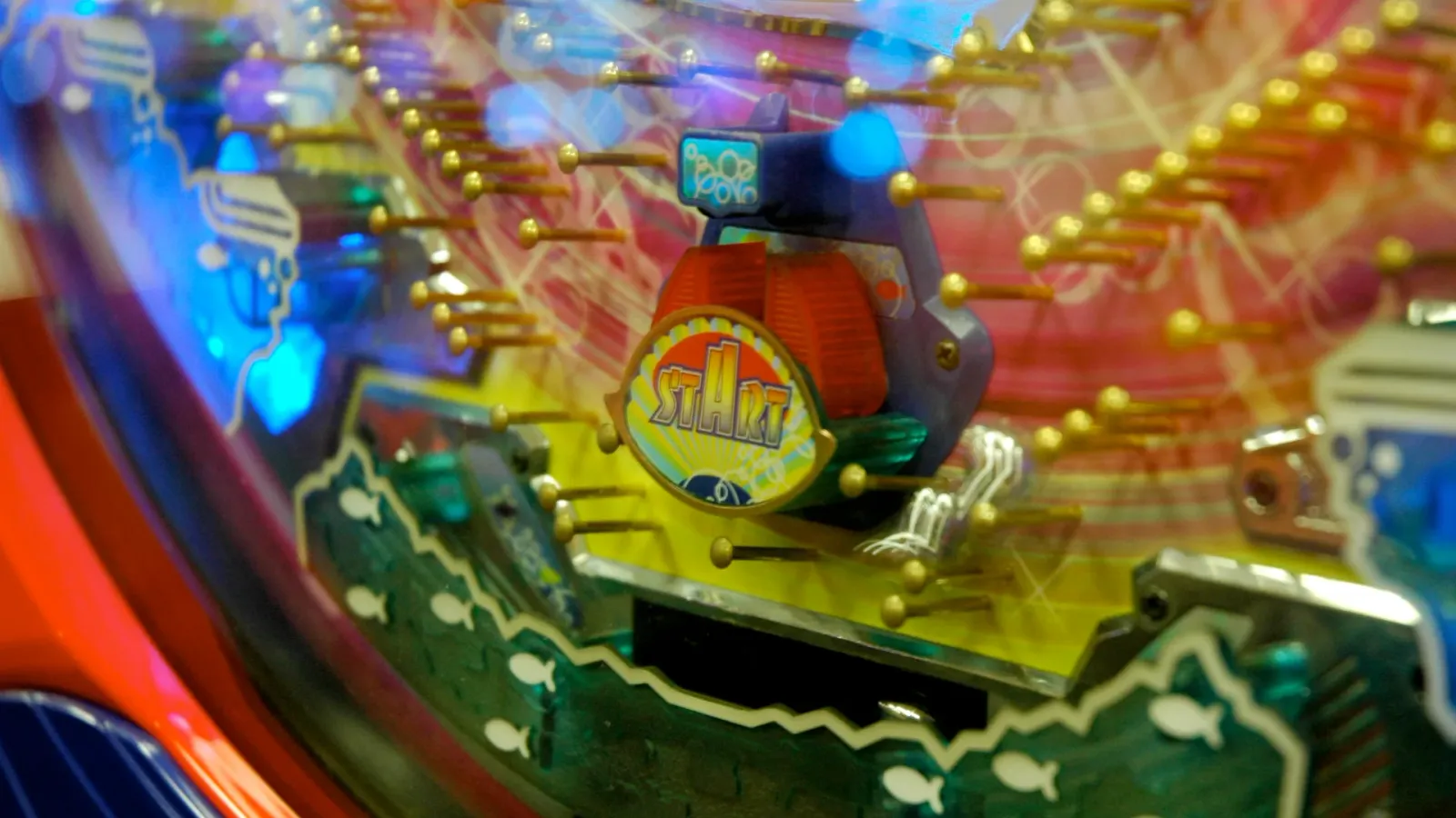 Close-up of a pachinko machine's brass pins and colourful playfield